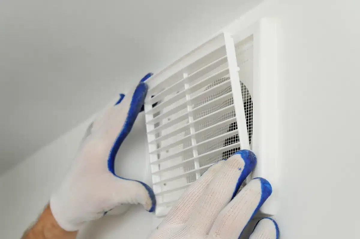 Un professionnel pose une grille de VMC pour garantir un renouvellement d’air optimal et éviter l’humidité dans un habitat rénové.
